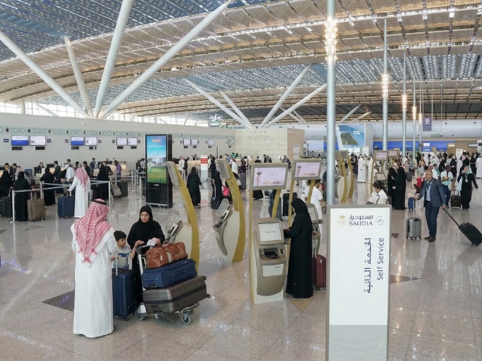 Busy international airport terminal in Saudi Arabia at King Abdulaziz International Airport Jeddah JED with passengers using self-service check-in kiosks and airline counters, representing premium airport fast track, VIP meet and assist services, and Altanfeethi.VIP elite airport concierge assistance for travelers.